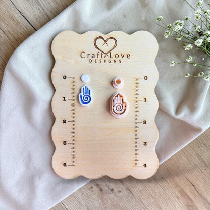 Polymer clay cutter and finished earrings displayed on wooden board