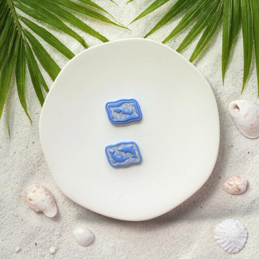Blue dolphin clay pieces shown on white plate with beach styled background