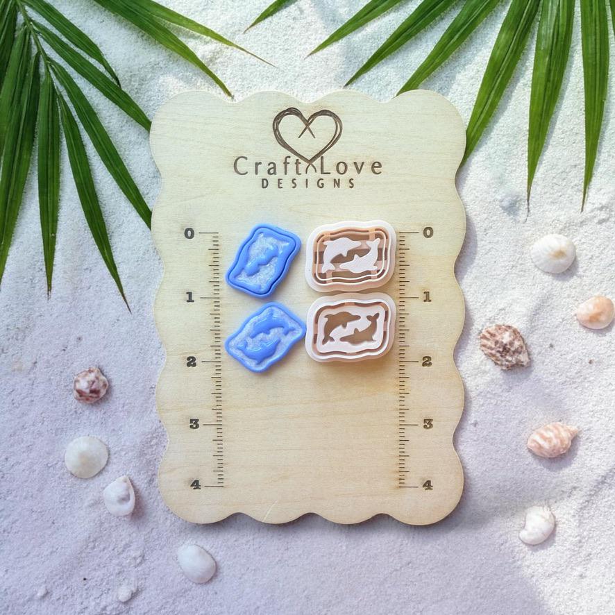Dolphin clay cutters and finished pieces shown on wooden sizing board with beach decor