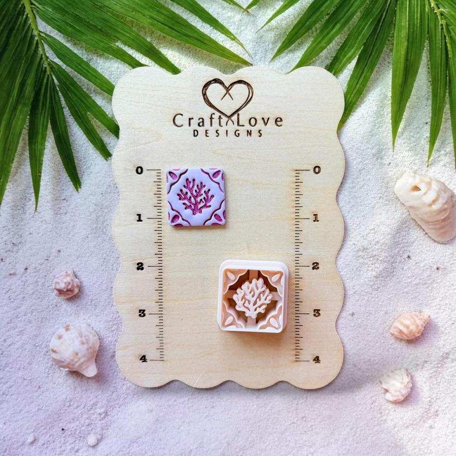 Coral tile clay piece and cutter displayed on wooden sizing board with seashells and tropical leaves
