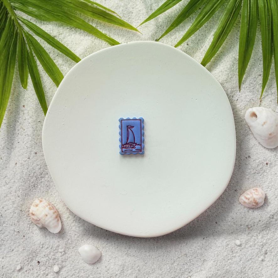 Blue sailboat clay piece made with frame design on white plate beach background