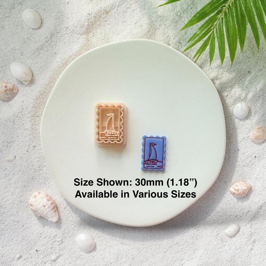 Sailboat frame cutter and finished clay pieces with size text 30mm on white plate with sand and shells