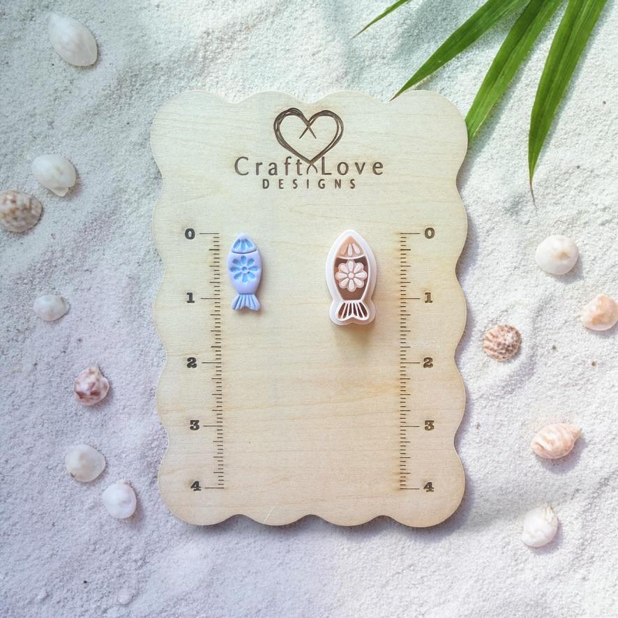 Fish clay cutter and finished pieces displayed on wooden sizing board with beach decor