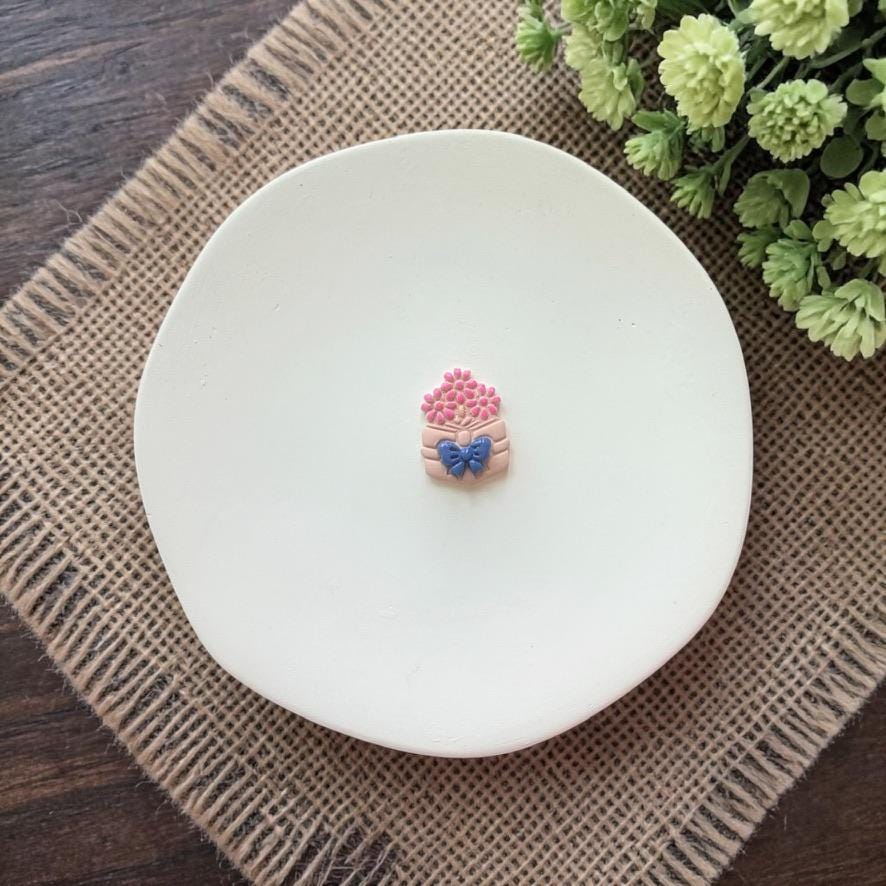 small book with flowers clay earring on white plate with rustic fabric