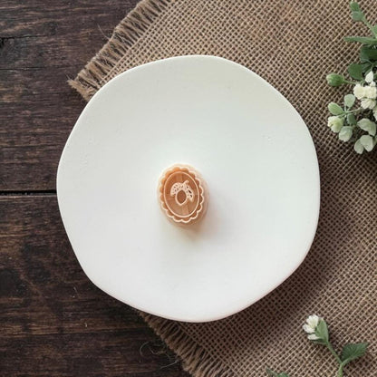 ornate lemon cameo clay piece on white plate burlap background