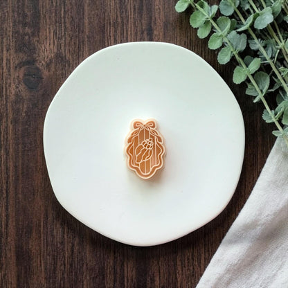 seashell cameo polymer clay cutter on white plate with wood background