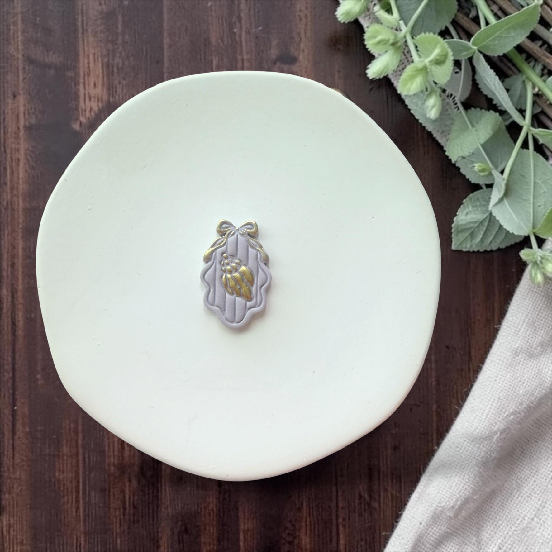 finished seashell cameo clay piece with bow detail on white plate