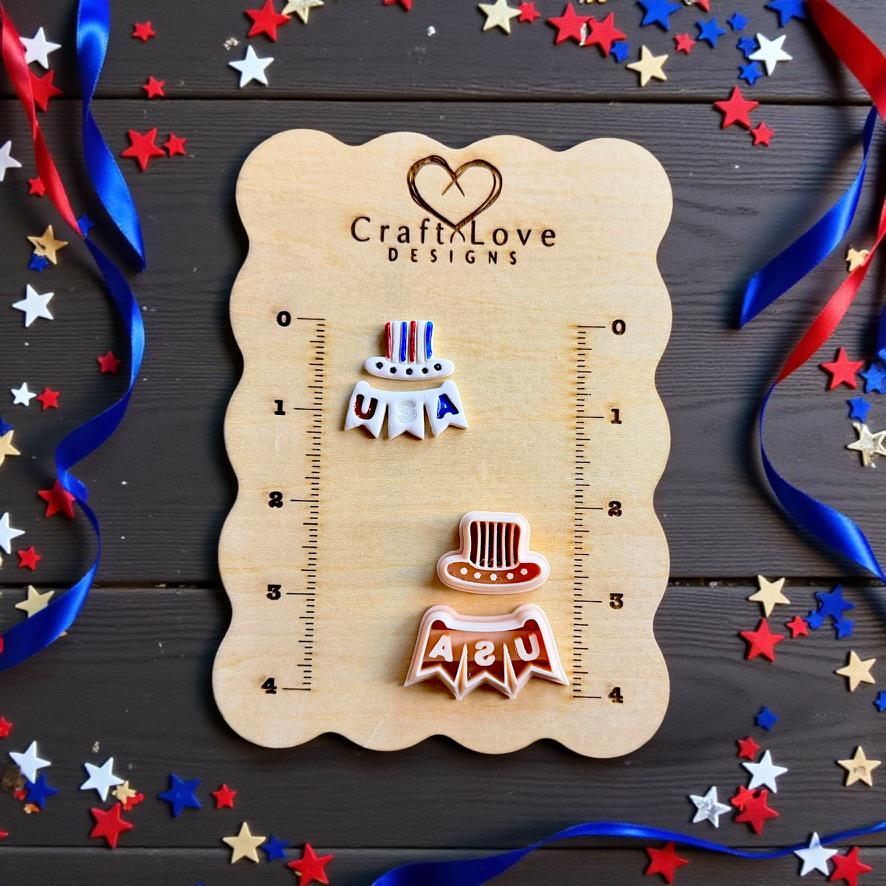 Patriotic polymer clay earring cutters displayed on a wooden ruler board with red white and blue ribbon and star confetti decorations