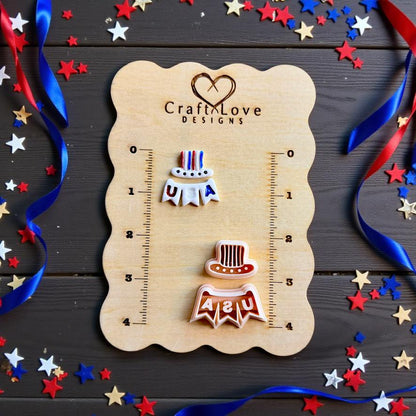 Patriotic polymer clay earring cutters displayed on a wooden ruler board with red white and blue ribbon and star confetti decorations