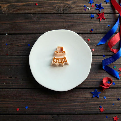 Patriotic Uncle Sam hat and USA banner polymer clay cutter set displayed on a white round surface with red white and blue ribbon decorations