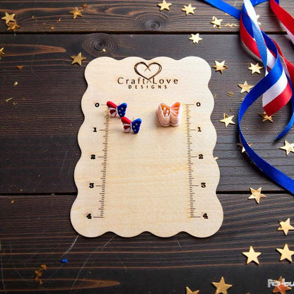 Patriotic butterfly clay earrings and matching cutter displayed on wooden measurement board with gold stars and ribbon