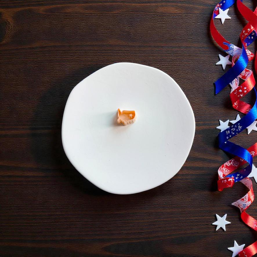 Small USA map polymer clay cutter displayed on white clay surface with patriotic ribbon and stars