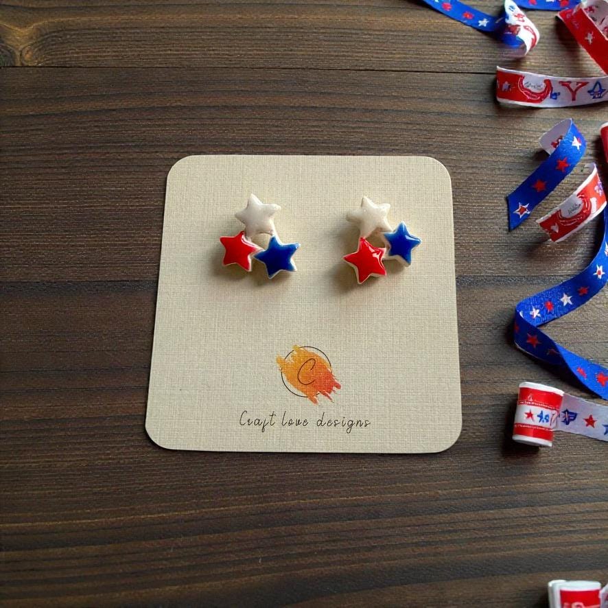 Patriotic red white and blue star stud earrings displayed on jewelry card with festive ribbon decorations