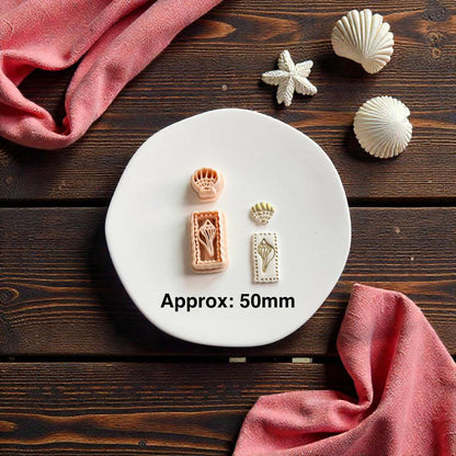 Seashell polymer clay cutter set displayed on white clay slab with beach themed seashell decorations and pink fabric