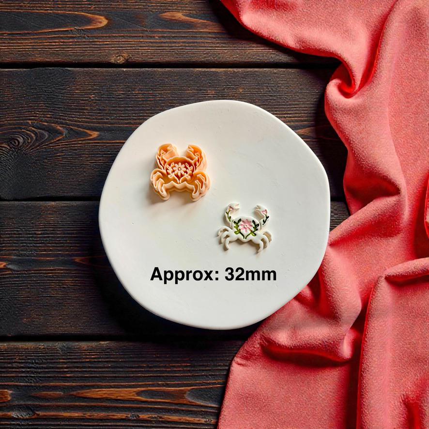 Folk inspired crab polymer clay cutter and finished crab clay earring shown together with approximate 32mm sizing text on white ceramic plate
