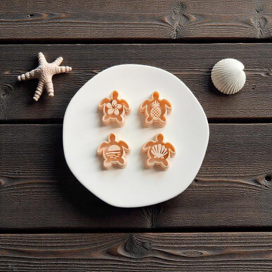 Four sea turtle polymer clay cutters with tropical center designs displayed on white ceramic plate with beach themed coastal decor