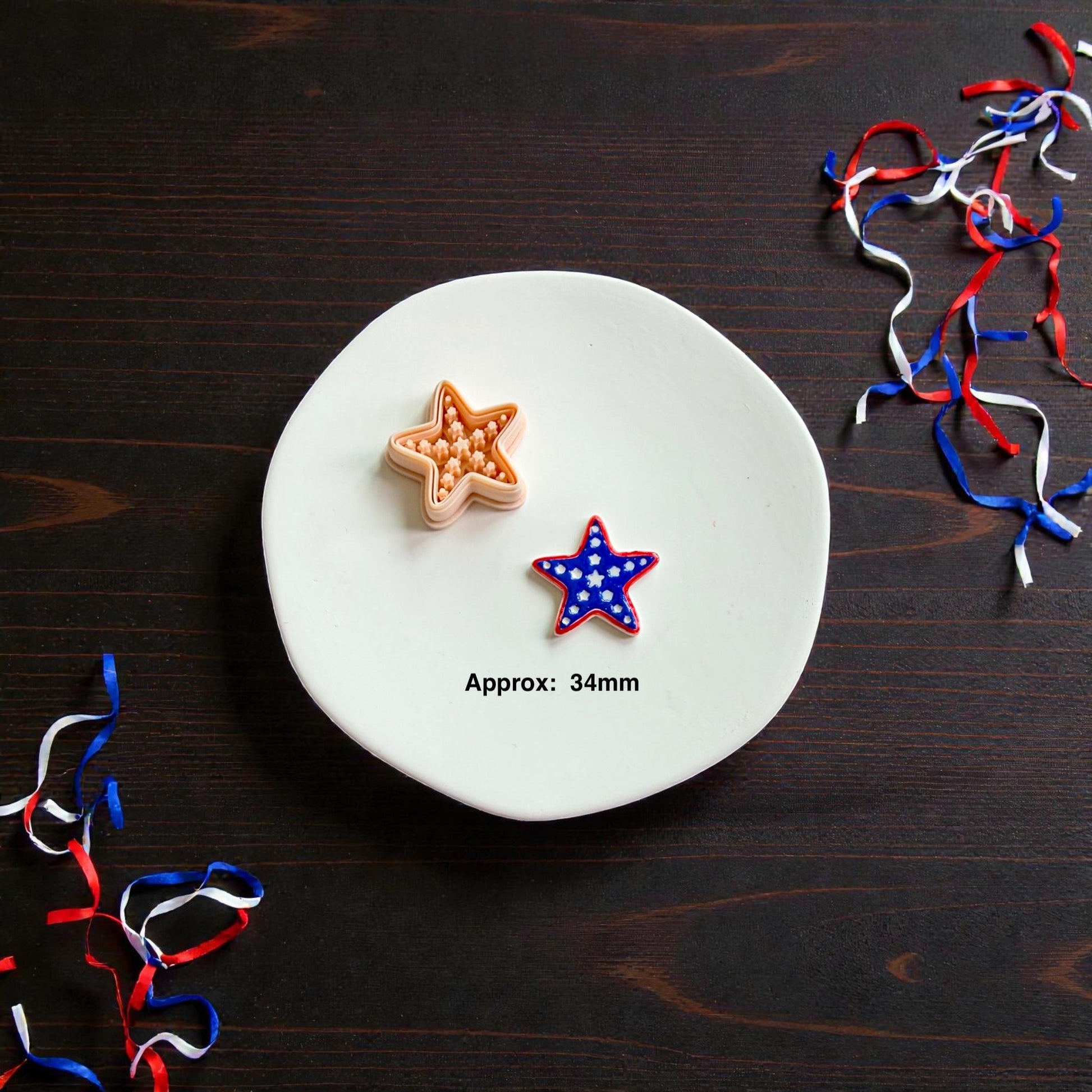 Patriotic starfish polymer clay cutter with matching red white and blue finished clay earring displayed on white ceramic plate with ribbon decor
