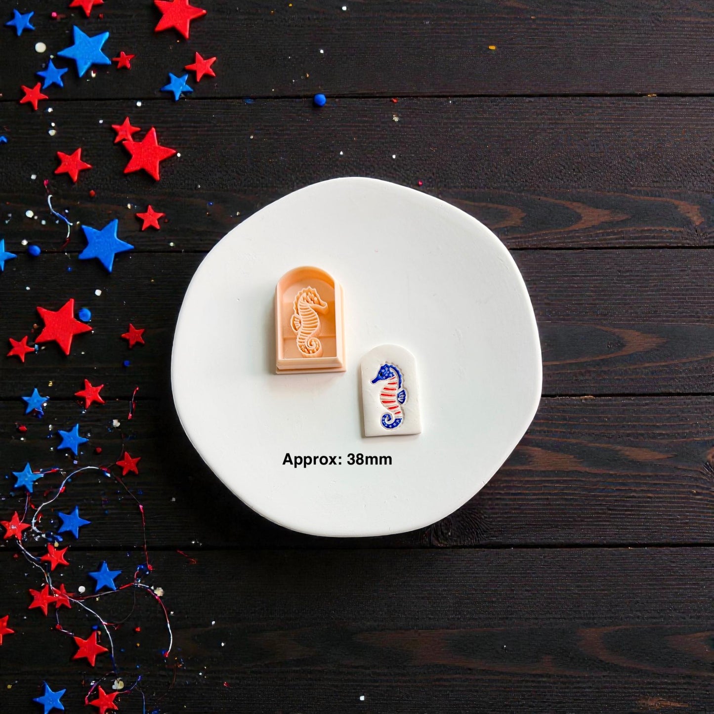 Patriotic seahorse polymer clay cutter with finished clay design displayed on white ceramic plate showing approximate 38mm size