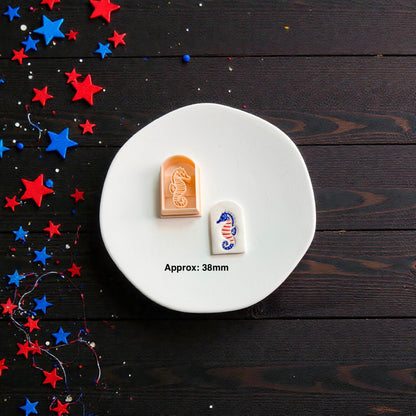 Patriotic seahorse polymer clay cutter with finished clay design displayed on white ceramic plate showing approximate 38mm size