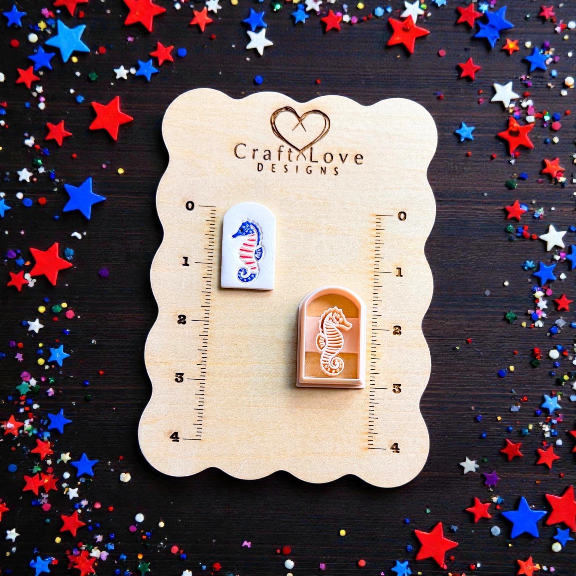 Patriotic seahorse polymer clay cutter and finished Americana seahorse clay piece displayed on CraftLove Designs wooden measurement board with red white and blue confetti