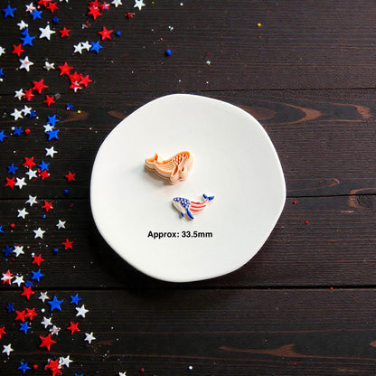 Patriotic whale polymer clay cutter and finished Americana whale clay piece displayed on white ceramic plate with red white and blue confetti