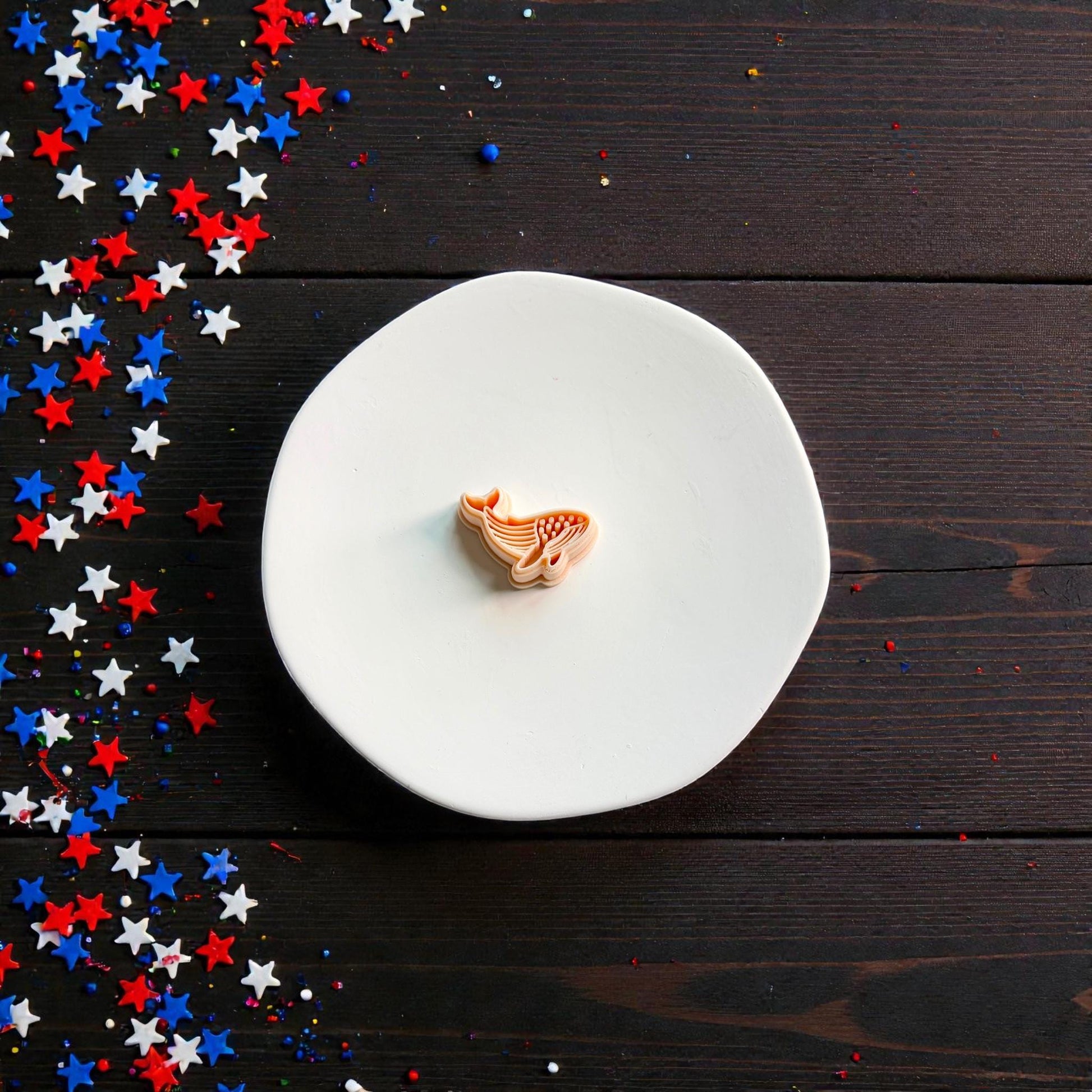 Patriotic whale clay cutter displayed on white ceramic plate with festive Fourth of July star decorations