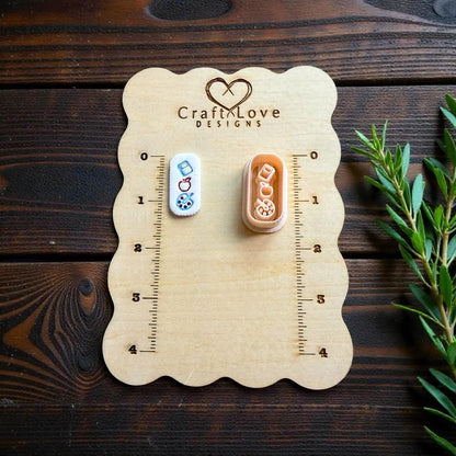 Teacher earrings clay cutter displayed on CraftLove Designs wooden measurement board with rustic wood background and greenery