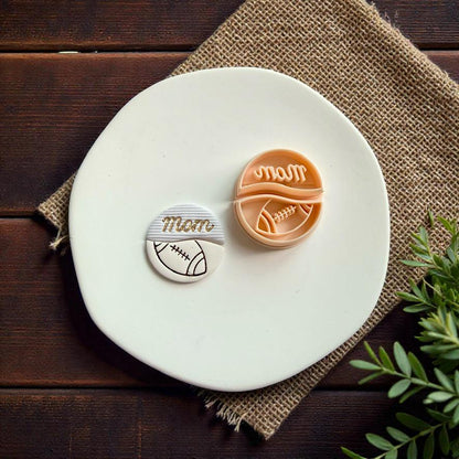 Finished football mom polymer clay earring and cutter displayed on white ceramic plate with rustic wood background