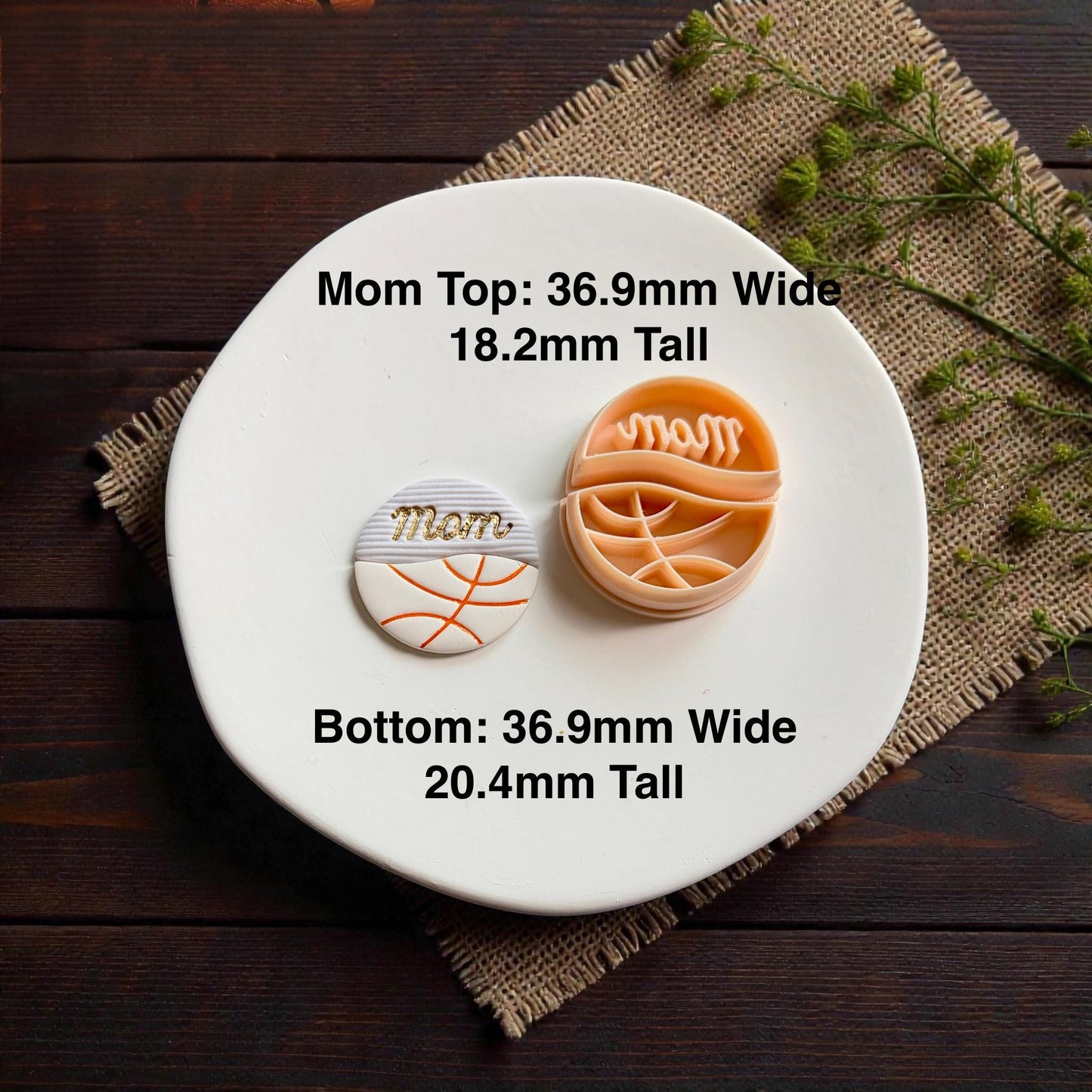 Finished basketball mom polymer clay earring and cutter displayed on white ceramic plate with rustic wood background
