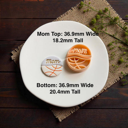 Finished basketball mom polymer clay earring and cutter displayed on white ceramic plate with rustic wood background