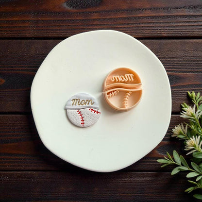 Finished baseball mom polymer clay earring and cutter displayed on white ceramic plate with rustic wood background