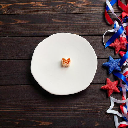 Small butterfly polymer clay cutter displayed on white surface with patriotic ribbon decorations