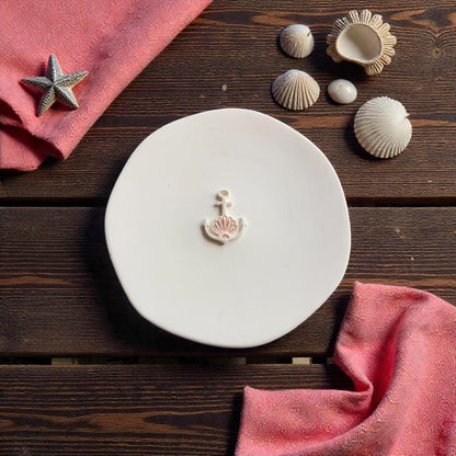 Coastal anchor clay cutter for polymer clay earrings shown on white ceramic plate with beach themed seashell props