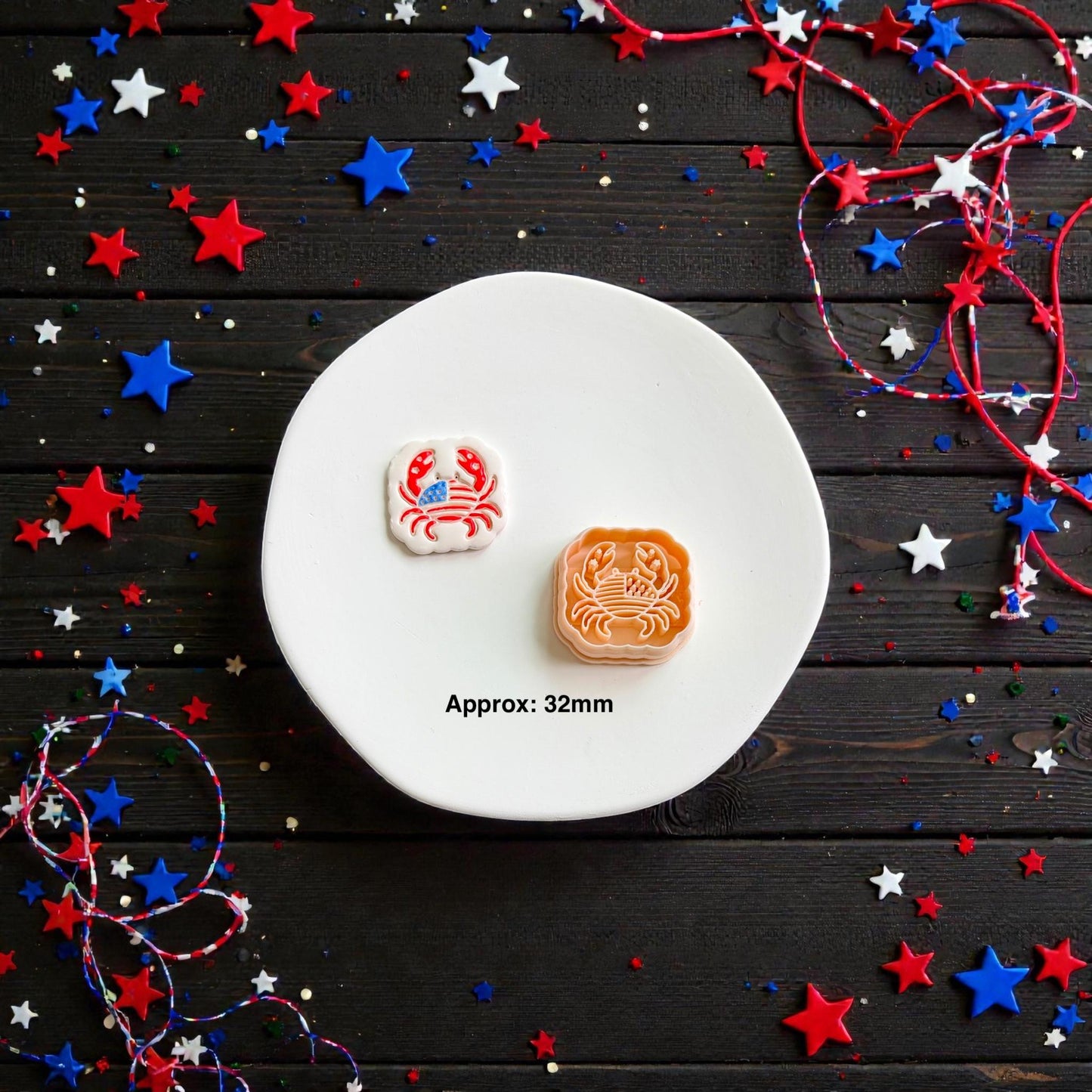Patriotic crab clay cutter with matching finished Americana crab earring displayed on white ceramic plate with festive red white and blue decor