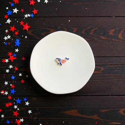 Finished patriotic whale clay piece featuring red white and blue Americana design displayed on white ceramic plate