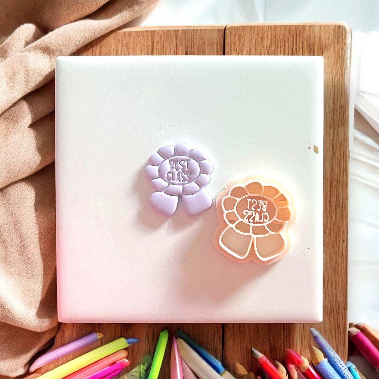 Two polymer clay cutters on a white surface with colorful markers below.