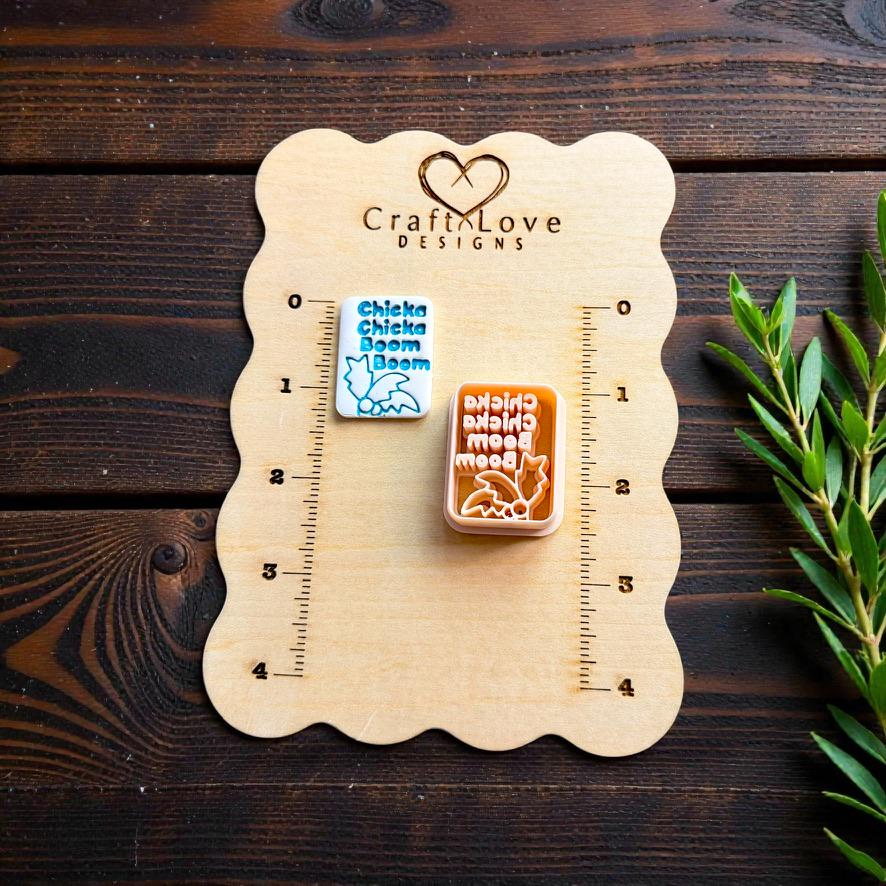 Alphabet inspired polymer clay cutter displayed on CraftLove Designs wooden measurement board with greenery accents