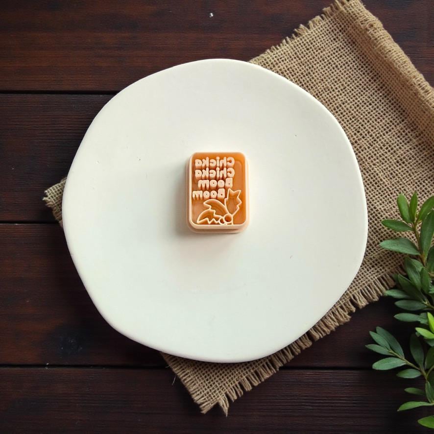 Alphabet inspired cutter tool displayed alone on white ceramic plate with rustic wood background and greenery