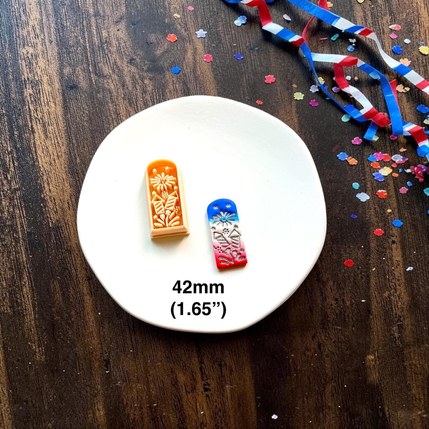 Patriotic fireworks polymer clay cutter next to completed clay example showing 42mm size measurement on a white ceramic plate