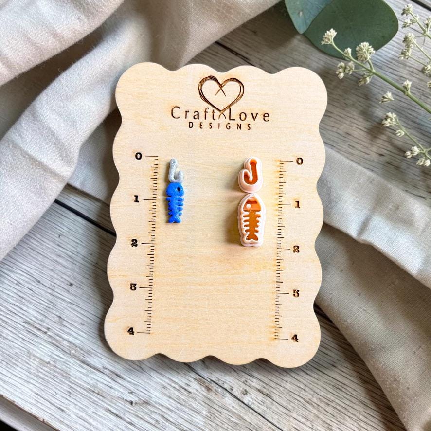 Finished fish bone charm and matching polymer clay cutters displayed on a CraftyLove Designs sizing board.