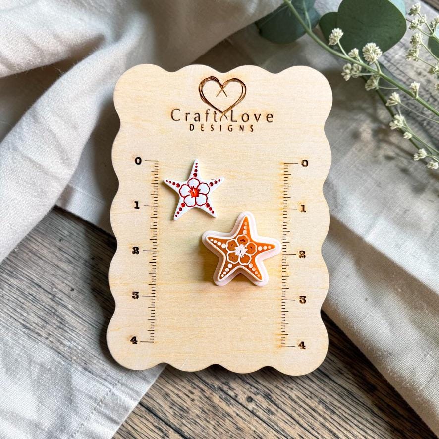 Finished starfish polymer clay earring beside the matching starfish cutter displayed on a CraftyLove Designs sizing board.