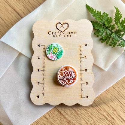 Finished tropical sea turtle polymer clay earring displayed beside the matching cutter on a Craft Love Designs sizing board.