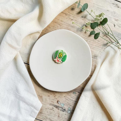 Sea turtle polymer clay cutter with tropical leaves and hibiscus design displayed on a white ceramic plate.