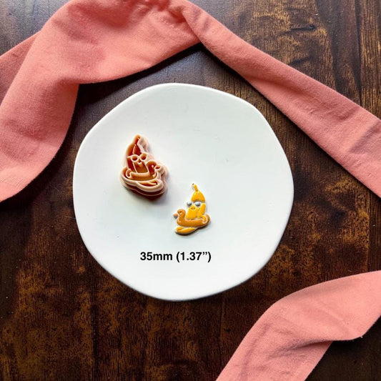Finished banana floatie clay piece on white plate with coral fabric