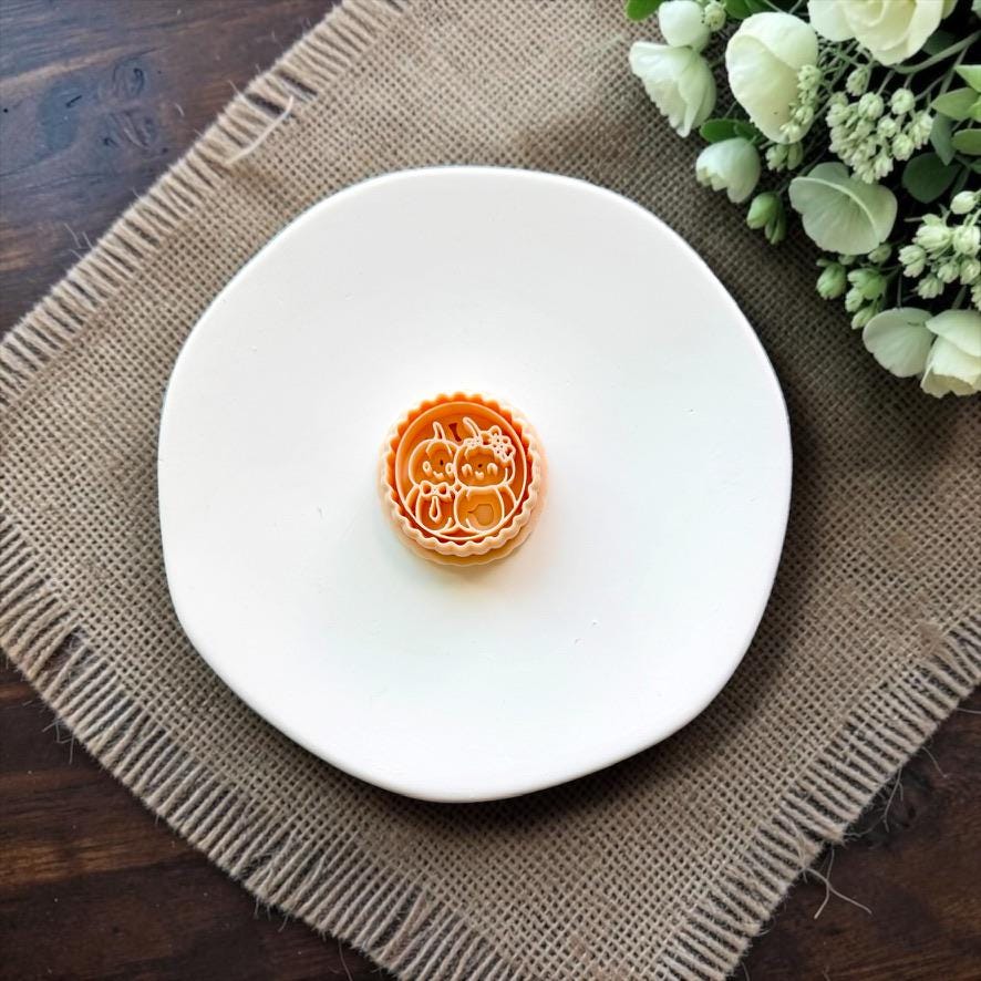 Mr and Mrs Pumpkin polymer clay cutter displayed on a white ceramic dish.