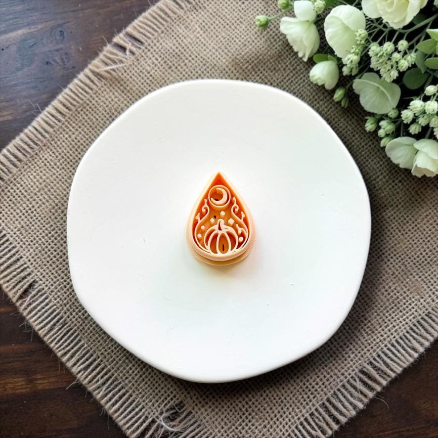 Halloween pumpkin teardrop polymer clay cutter displayed on a white ceramic dish.