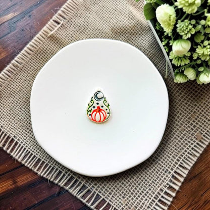Halloween pumpkin teardrop embossed polymer clay sample displayed on a white ceramic dish.