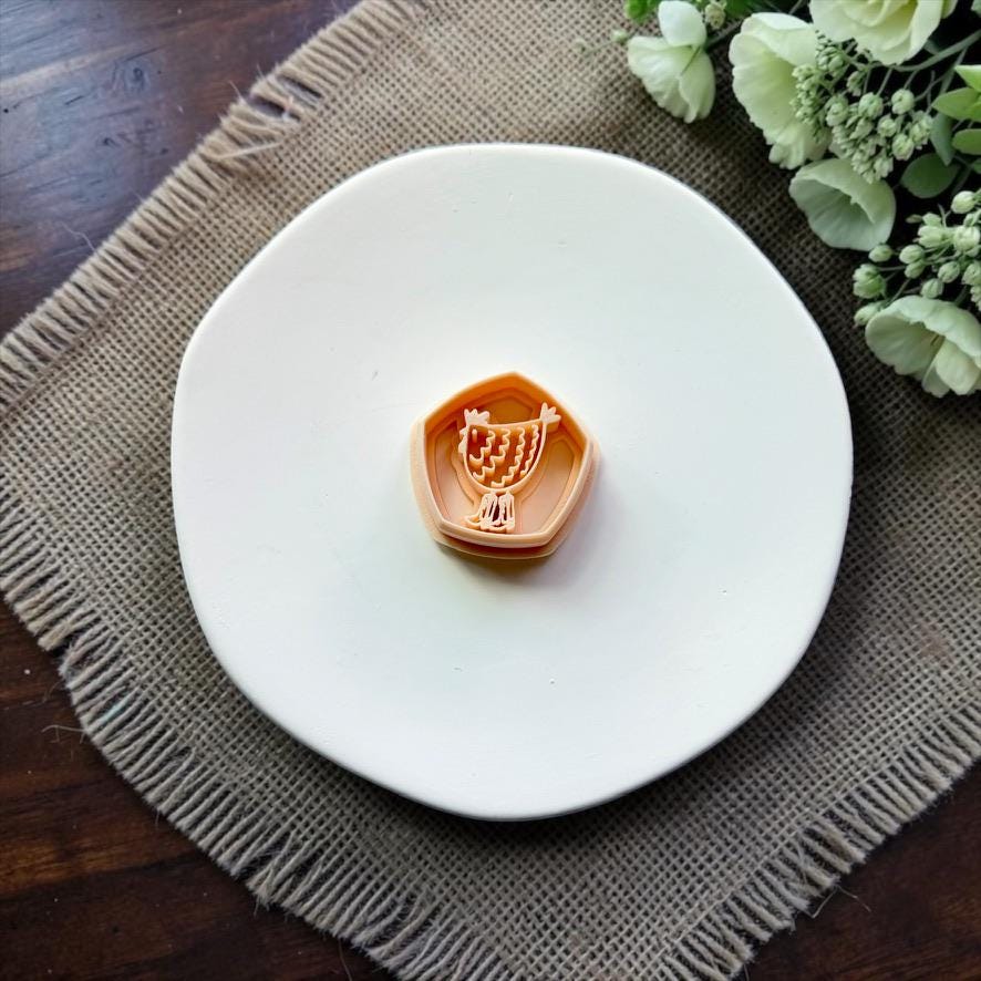 Chicken polymer clay cutter displayed on a white ceramic dish.