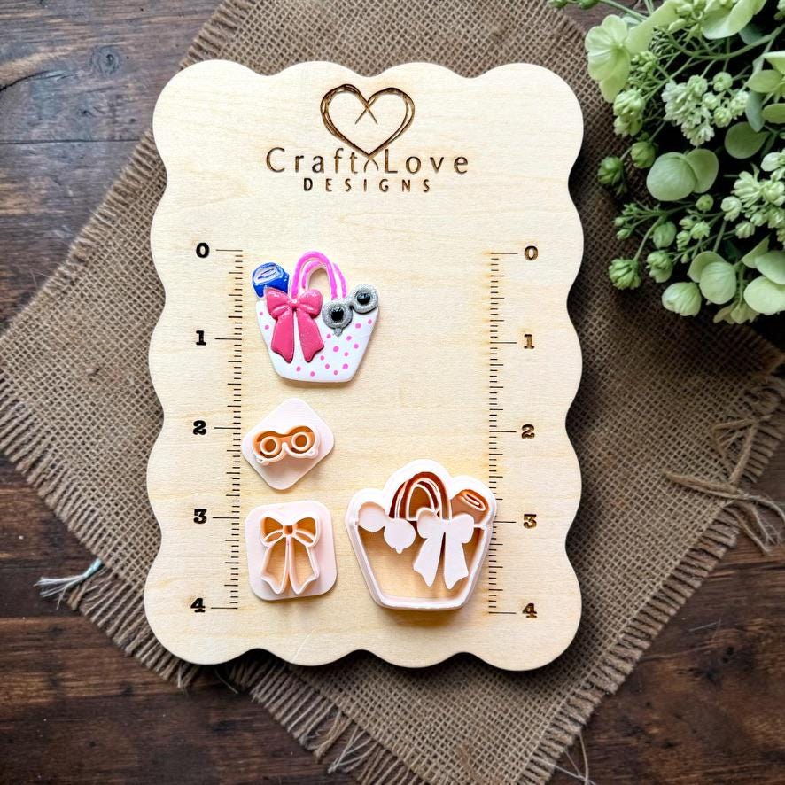 Finished summer handbag clay earring displayed with the cutter, bow, and sunglasses stamps on the Craft Love Designs measurement board.