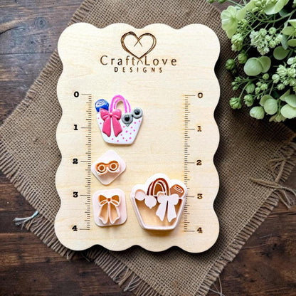 Finished summer handbag clay earring displayed with the cutter, bow, and sunglasses stamps on the Craft Love Designs measurement board.